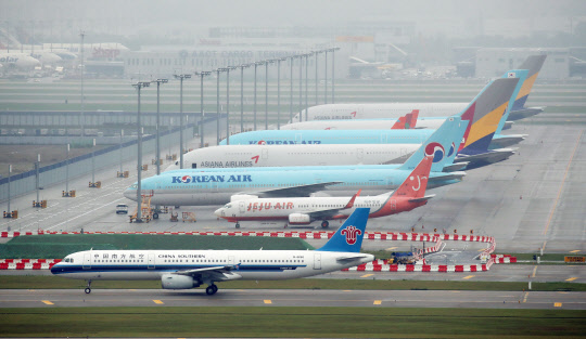 지난달 29일 오후 영종도 인천국제공항 주기장에 멈춰선 항공기들 앞으로 중국남방항공 소속 항공기가 지나고 있다.    영종도=연합뉴스
